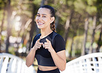 Fitness woman smiling and pointing her index fingers at the camera while out for a run at the park. Cheerful female athlete motivating you to exercise and take care of your health