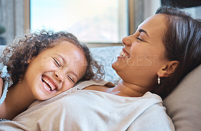 Joyful mother and little daughter lying her head on her mothers chest as they laugh and spend time together at home. Sweet moments between mother and child