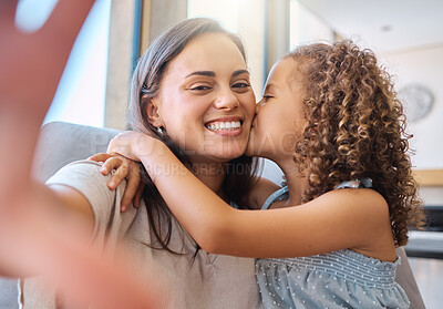Buy stock photo Adorable little girl kissing her mother on the cheek while they take a selfie together. Young mom holding cellphone and taking self-portrait with loving child