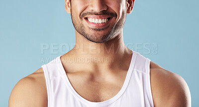 Closeup young man showing teeth in studio isolated against a blue background. Mixed race male wearing a vest, looking confident and happy with his dental and oral hygiene. Brush for good gum health