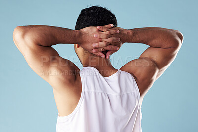 Rearview young mixed race man wearing a vest in studio isolated against a blue background. Unrecognizable male athlete standing with his hands behind his head during a break from his workout exercise