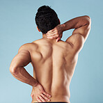 Rearview young mixed race man standing shirtless in studio isolated against a blue background. Unrecognizable topless male athlete suffering from back pain or ache. He's picked up a fitness injury