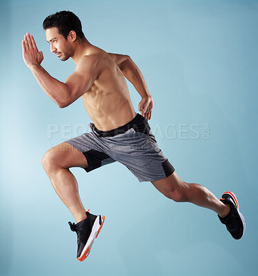 Buy stock photo Fullbody young hispanic man running in studio isolated against a blue background. Mixed race shirtless male athlete running or sprinting to win a race. Endurance training to increase his cardio