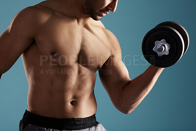 Buy stock photo Closeup young hispanic man training with dumbbells in studio isolated against a blue background. Mixed race shirtless male athlete exercising or working out to increase his strength and fitness