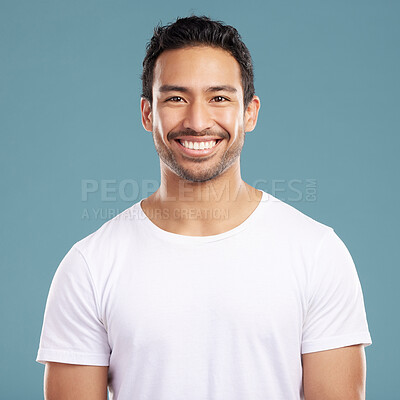 Buy stock photo Handsome young mixed race man smiling and happy while standing in studio isolated against a blue background. Hispanic male in casual wear expressing happiness with a smile and looking at the camera