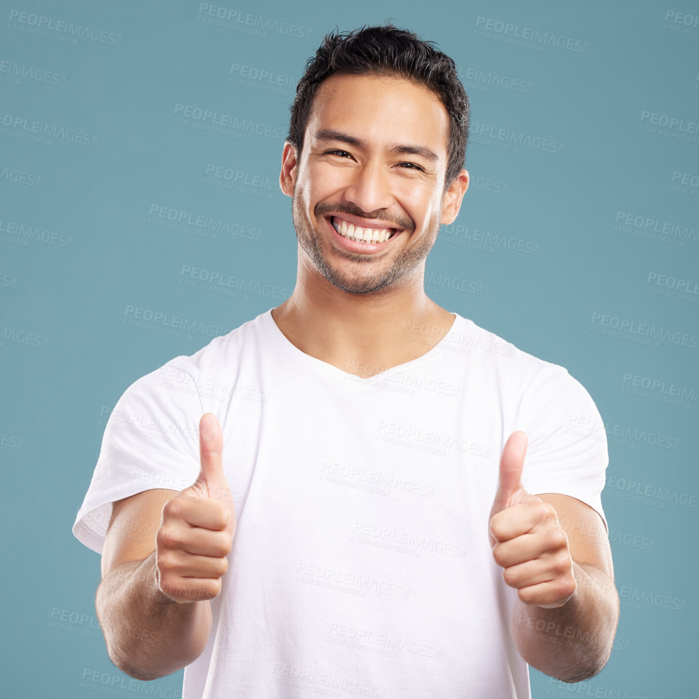 Buy stock photo Handsome young mixed race man giving thumbs up while standing in studio isolated against a blue background. Hispanic male showing support or appreciation. Backing or endorsing a product or company