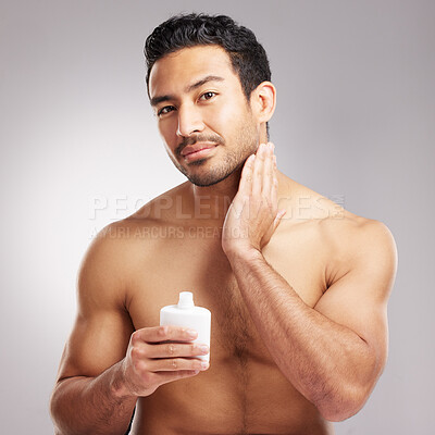 Buy stock photo Handsome young mixed race man shirtless in studio isolated against a grey background. Hispanic male applying aftershave after shaving. Take care of your skin when you groom or shave your beard and face