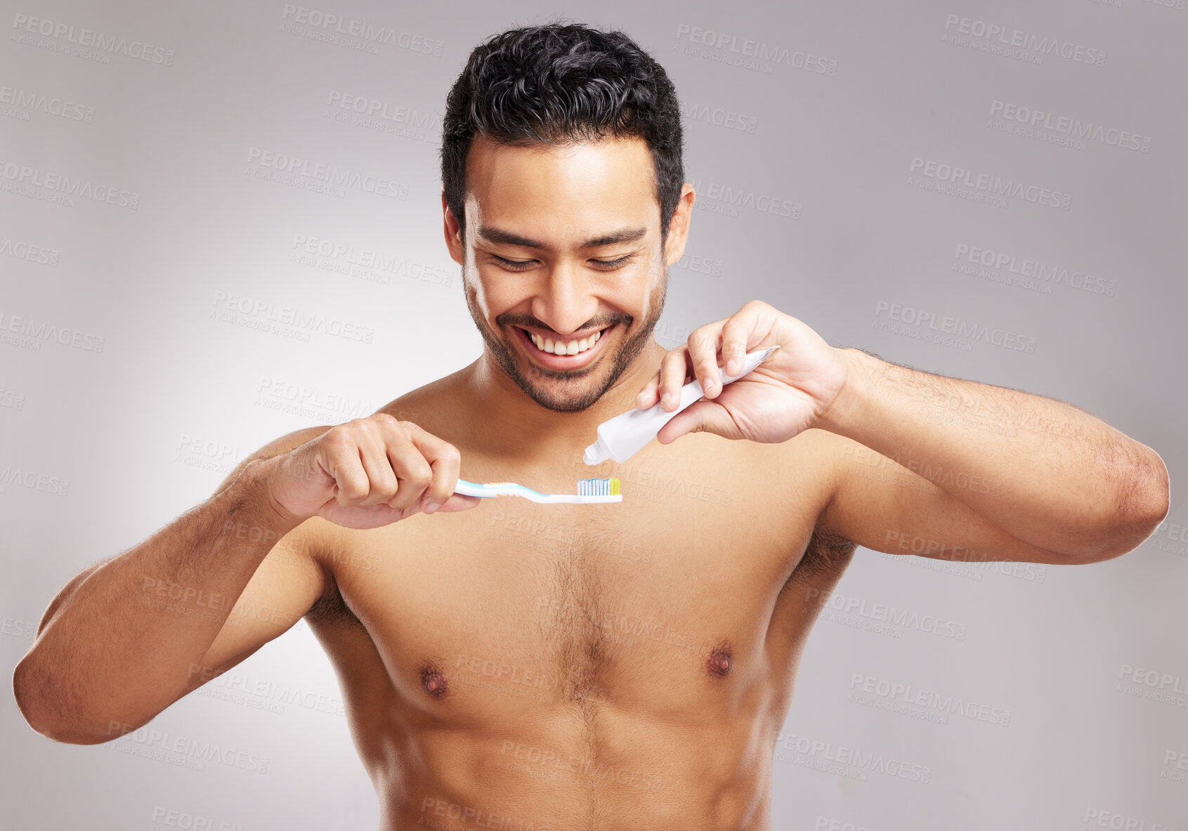 Buy stock photo Closeup young mixed race man shirtless in studio isolated against a grey background. Hispanic male brushing his teeth. Taking caring of mouth and oral hygiene to promote dental health and healthy gums