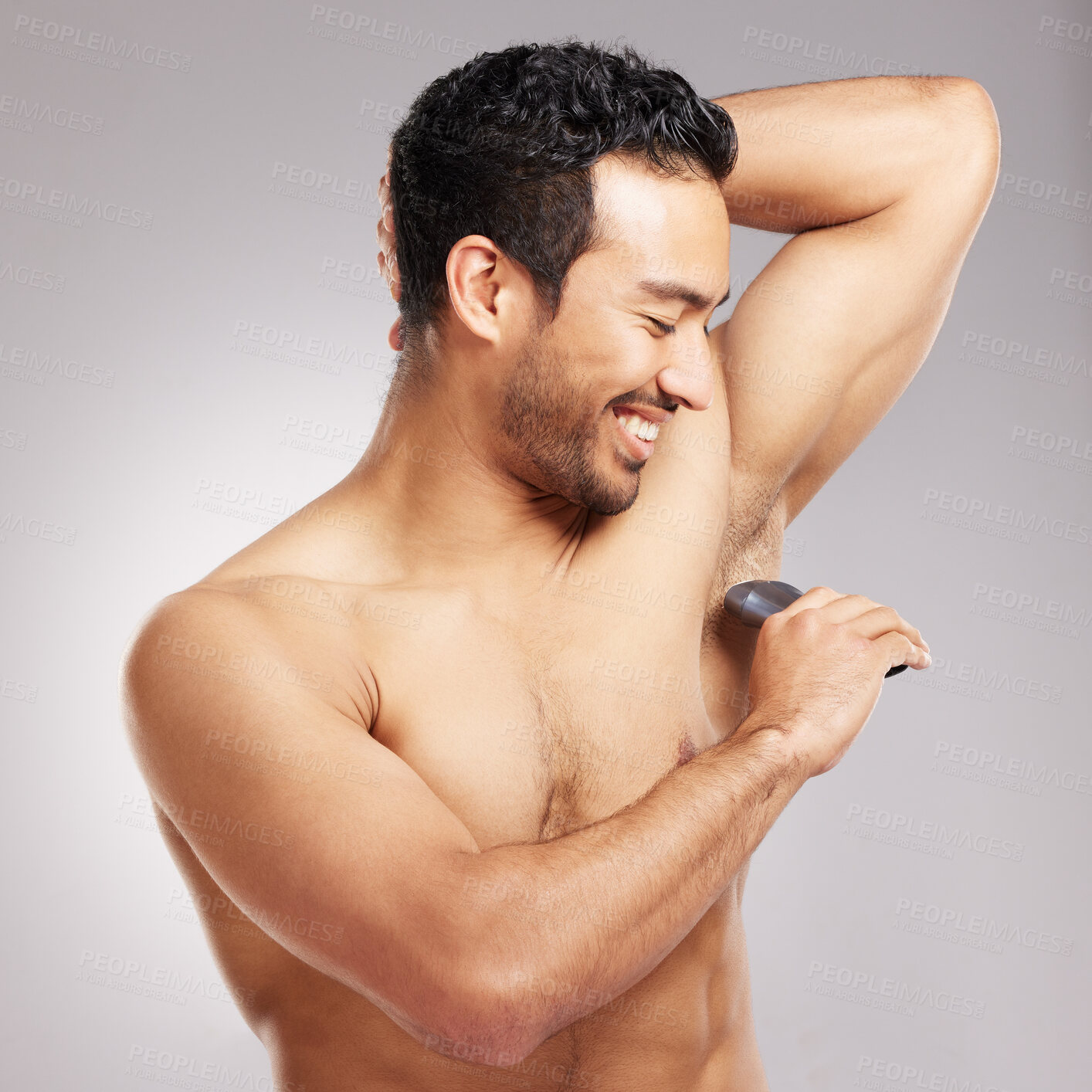 Buy stock photo Handsome young mixed race man shirtless in studio isolated against a grey background. Hispanic male using an electric razor to shave his underarms. Healthy and fresh, shaving is part of his grooming