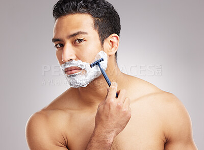 Buy stock photo Handsome young mixed race man shirtless in studio isolated against a grey background. Hispanic male using a razor while shaving. Take care of your skin when you groom or shave your beard and face