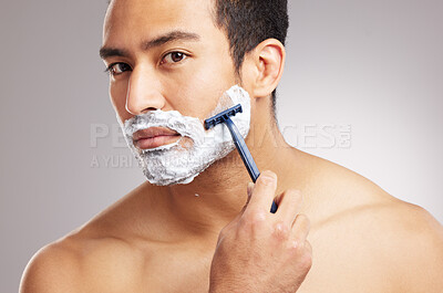 Buy stock photo Handsome young mixed race man shirtless in studio isolated against a grey background. Hispanic male using a razor while shaving. Take care of your skin when you groom or shave your beard and face