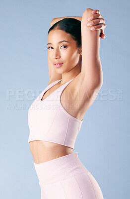 Buy stock photo Mixed race fitness woman stretching in studio against a blue background. Beautiful young hispanic female athlete warming up for exercising or working out. Dedicated to a fit and healthy lifestyle