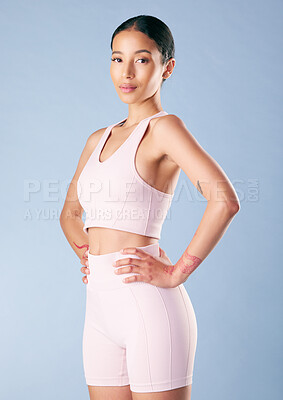 Buy stock photo Mixed race fitness woman standing with her hands on her hips in studio against a blue background. Beautiful young hispanic female athlete exercising or working out. Dedicated to health and fitness