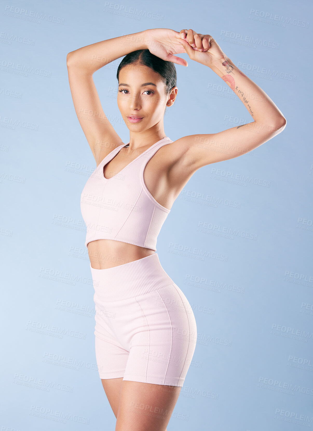 Buy stock photo Mixed race fitness woman stretching in studio against a blue background. Beautiful young hispanic female athlete warming up for exercising or working out. Dedicated to a fit and healthy lifestyle