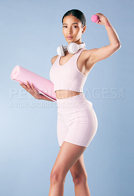 Buy stock photo Mixed race fitness woman standing with her yoga mat and flexing her bicep in studio against a blue background. Beautiful young hispanic female athlete exercising or working out. Health and fitness