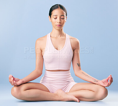 Buy stock photo Mixed race fitness woman meditating and practising yoga in studio against a blue background. Young hispanic female finding her center, inner peace and balance. Being mindful on her journey to zen