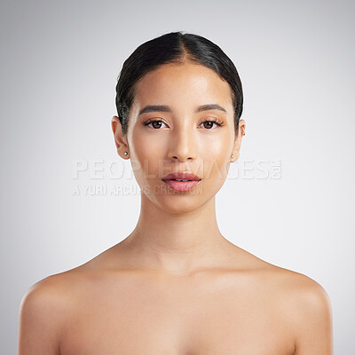 Buy stock photo Portrait of a confident young beautiful mixed race woman grooming and looking confident. A hispanic woman's selfcare routine for natural glowing skin against a grey studio copyspace background