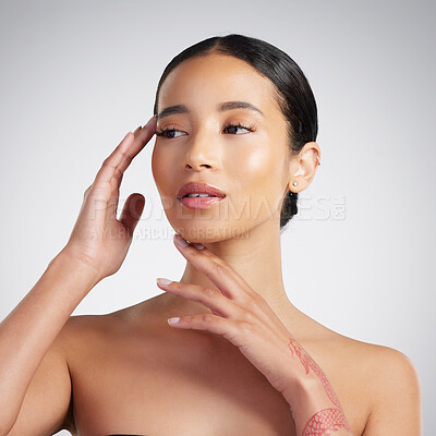 A beautiful young mixed race woman with glowing skin posing against grey copyspace background. Young confident woman doing a routine selfcare grooming routine with glowing radiant skin in a studio