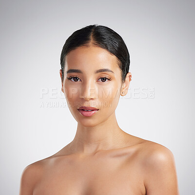 Portrait of a confident young beautiful mixed race woman grooming and looking confident. A hispanic woman\'s selfcare routine for natural glowing skin against a grey studio copyspace background