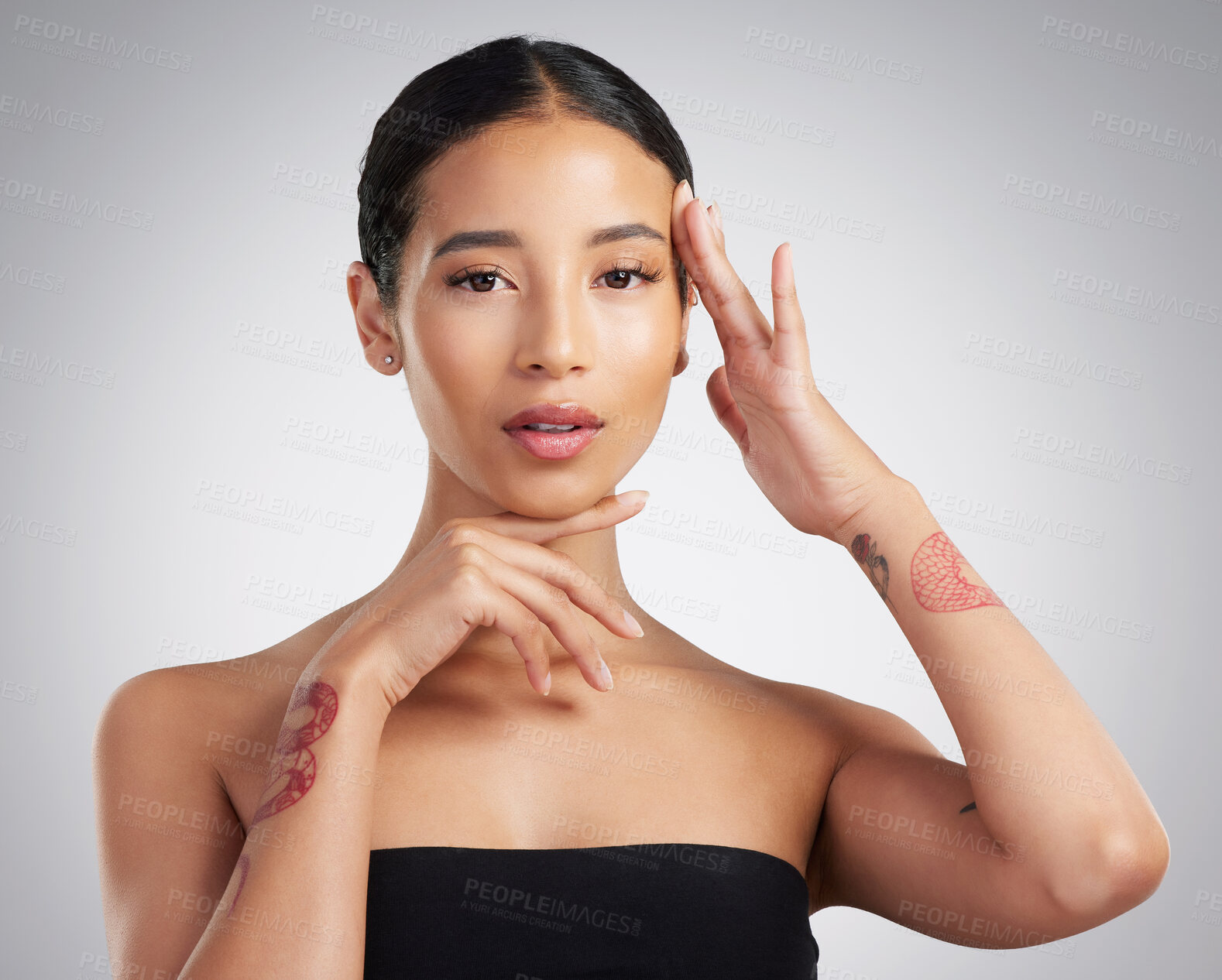 Buy stock photo Portrait of a beautiful mixed race woman touching smooth soft skin in a studio. Hispanic model with healthy natural glowing skin looking confident against grey copyspace while doing routine skincare