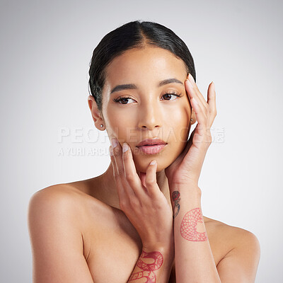 A beautiful young mixed race woman with glowing skin posing against grey copyspace background. Hispanic woman with natural looking eyelash extensions is a confident natural beauty in a studio