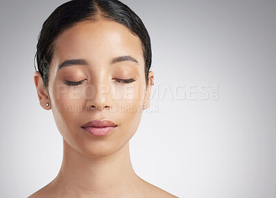 A beautiful young mixed race woman with glowing skin posing against grey copyspace background. Hispanic woman with natural looking eyelash extensions finds inner peace in a studio