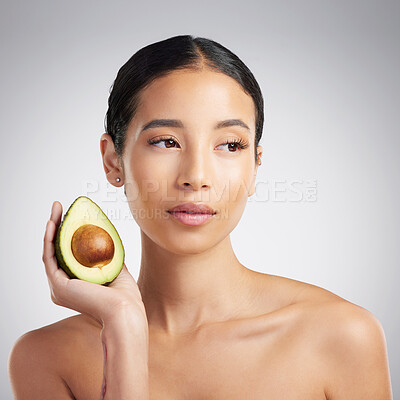 A gorgeous young mixed race woman holding an avocado. Hispanic model promoting the skin benefits of a healthy diet against a grey copyspace background