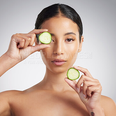 Studio Portrait of a beautiful mixed race woman holding cucumber slice. Hispanic model promoting the skin benefits of a healthy diet against a grey copyspace background