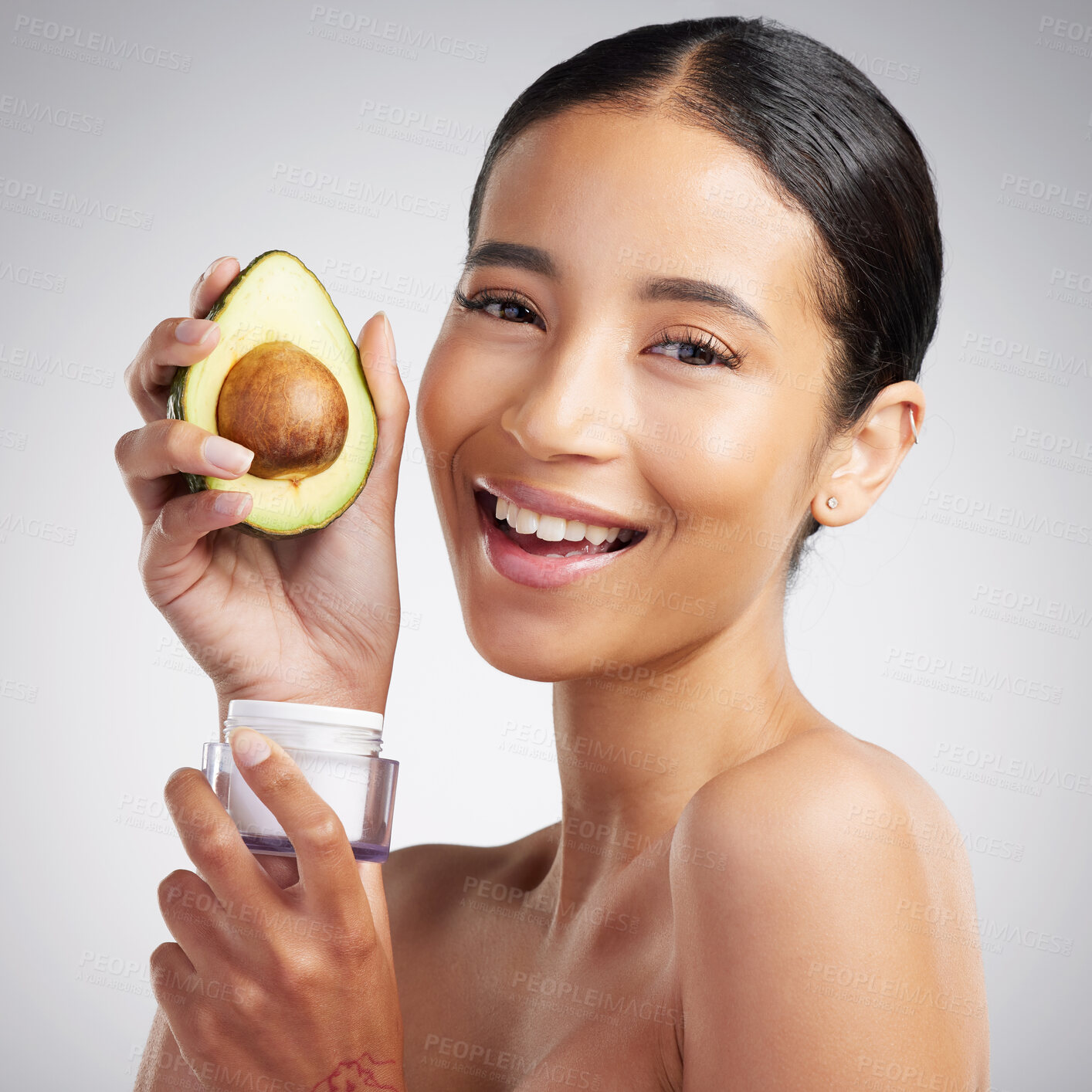 Buy stock photo Studio Portrait of a happy smiling mixed race woman holding an avocado product. Hispanic model with glowing skin promoting moisturiser against a grey copyspace background