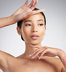 A beautiful young mixed race woman with glowing skin posing against grey copyspace background. Young confident woman doing a routine selfcare grooming routine with glowing radiant skin