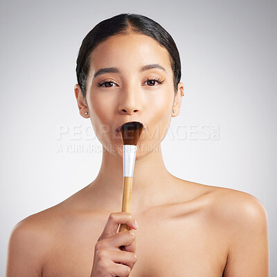 Buy stock photo Studio portrait of a beautiful mixed race woman posing with a makeup brush during a pamper routine. Hispanic model holding  a contouring brush against a grey