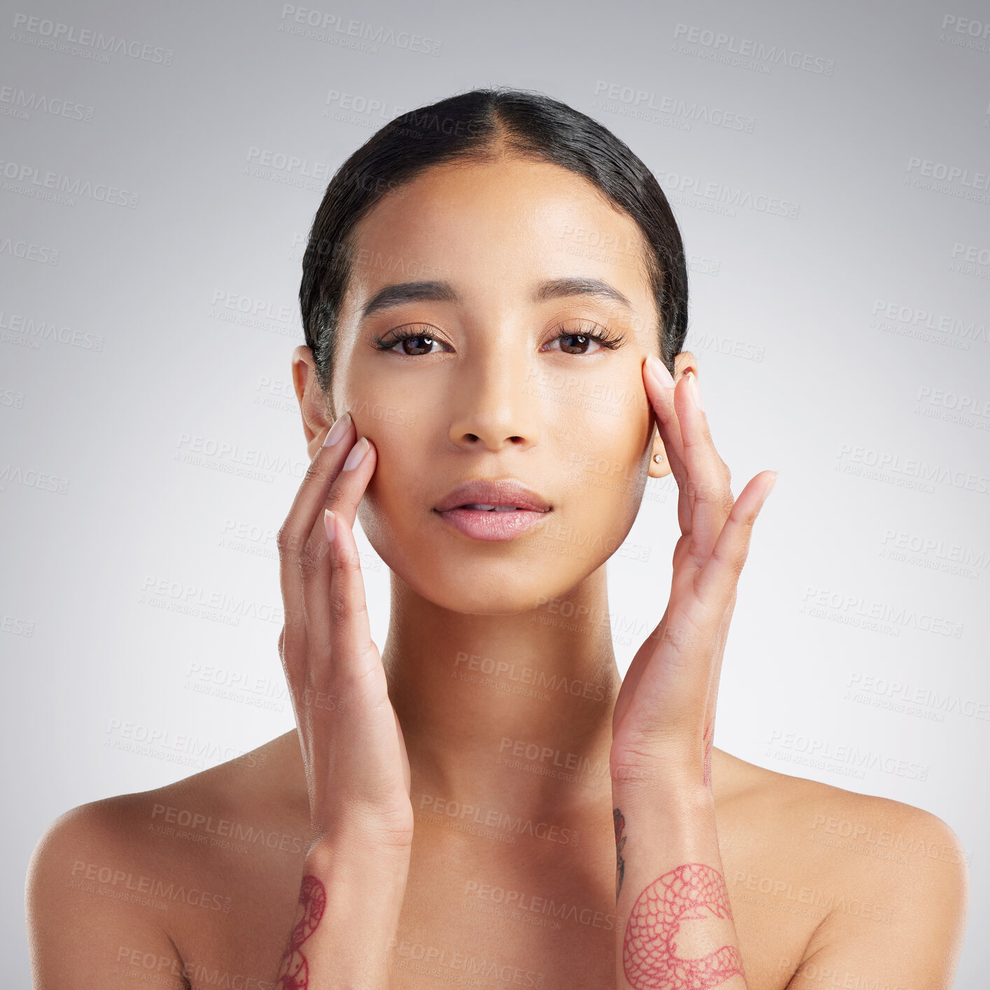 Buy stock photo Portrait of a beautiful mixed race woman touching smooth soft skin in a studio. Hispanic model with healthy natural glowing skin looking confident against grey copyspace while doing routine skincare