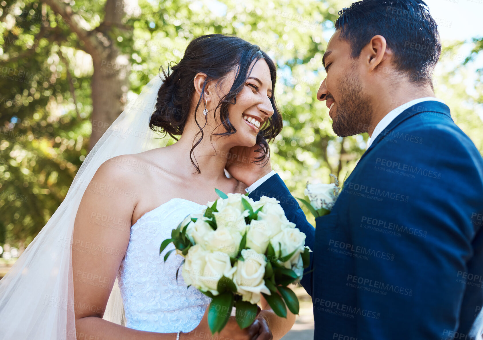 Buy stock photo Happy couple sharing moment on their wedding day. Bride and groom being affectionate on their special day. Woman holding bouquet while husband touches her face