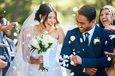 Buy stock photo Guests throwing confetti over bride and groom as they walk past after their wedding ceremony. Joyful young couple celebrating their wedding day
