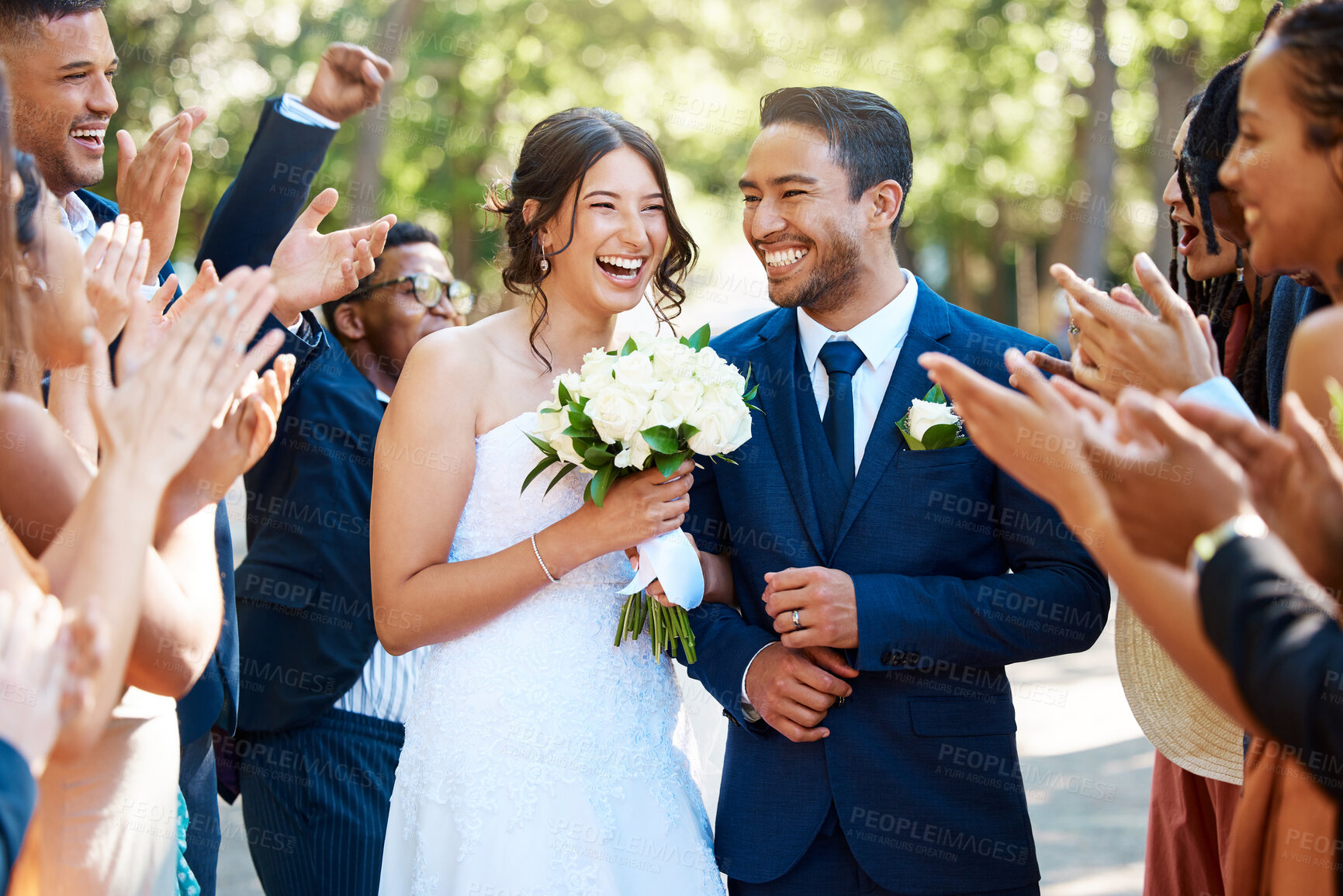 Buy stock photo Couple, wedding and guests clapping hands in celebration of love, romance and union. Happy, smile and young bride with a bouquet and groom walking by crowd cheering for marriage at an outdoor event.