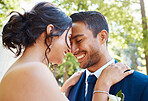 Happy young couple celebrating their marriage. Joyful bride and groom touching foreheads while standing together and sharing romantic moment on their wedding day