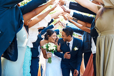 Buy stock photo Wedding guests forming a tunnel with their hands as newlywed couple walk through it. Bride and groom leaving their wedding reception