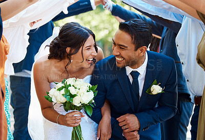 Buy stock photo Guests joining together to form a tunnel with their hands as newlywed couple walk through it. Bride and groom looking happy while supported by friends and family