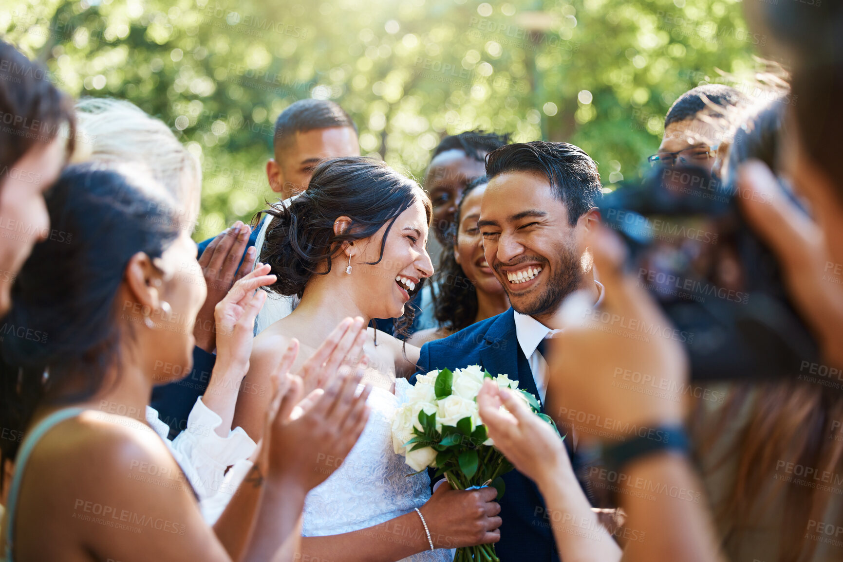 Buy stock photo Bride and groom looking joyful while surround by friends and family on their wedding day. Photographer capturing special moment as newlyweds and guests stand together