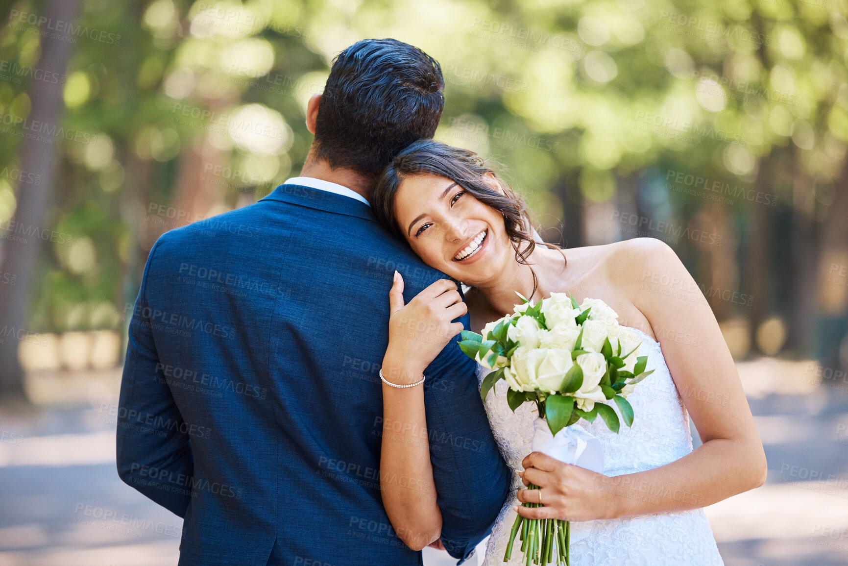 Buy stock photo Portrait of beautiful mixed race bride holding bouquet while standing with her groom and leaning on his shoulder in nature