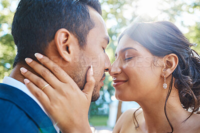 Buy stock photo Close up of young bride and groom enjoying romantic moments outside. Newlywed couple touching noses while standing face to face about to kiss