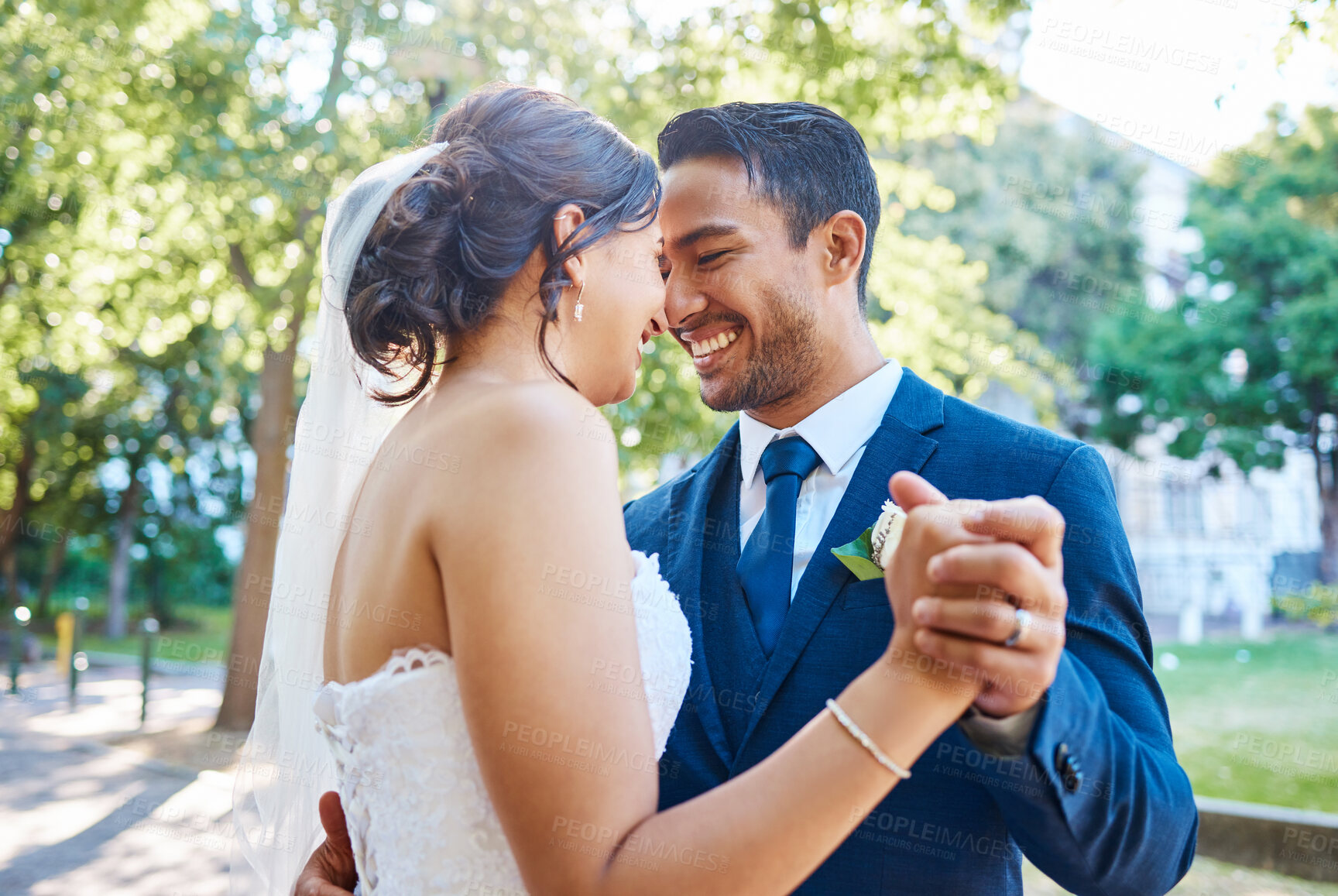 Buy stock photo Newlywed couple dancing outside. Mixed race bride and groom enjoying romantic moments on their wedding day. Happy young romantic couple sharing a dance in nature