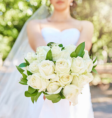 Close up of bride holding a bouquet of flowers while standing outside on a sunny day. Beautiful wedding bouquet of white roses