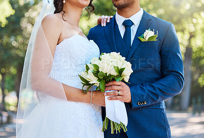 Buy stock photo Close up of a bride in her wedding dress and groom in suit holding on to a bouquet while standing together on their wedding day. Couple tying the knot. Wedding detail