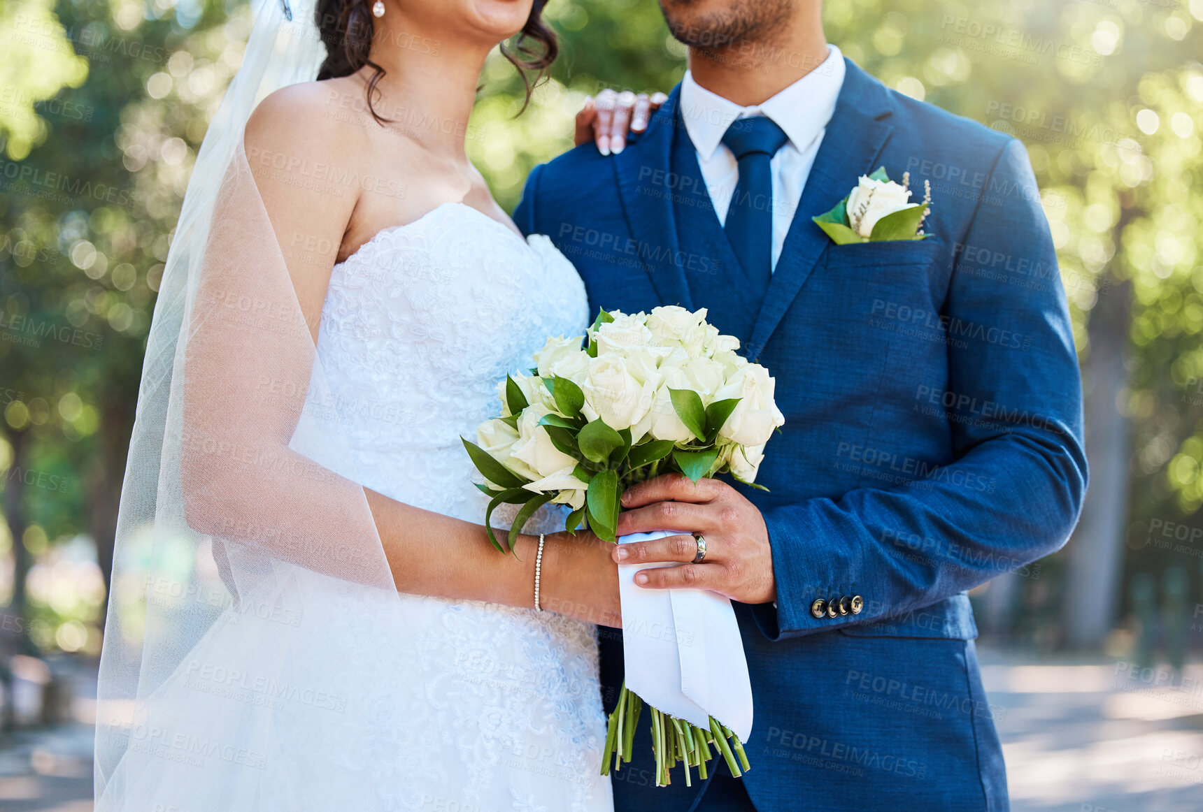 Buy stock photo Close up of a bride in her wedding dress and groom in suit holding on to a bouquet while standing together on their wedding day. Couple tying the knot. Wedding detail