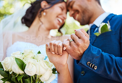 Closeup view showing hands of bride and groom couple on wedding day with ring bands on fingers. Newlyweds with pinky fingers interlocked making promise