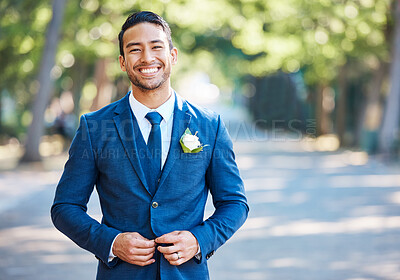 Buy stock photo Handsome groom wearing a blue suit with a white shirt and tie. Bridegroom fastening his jacket while standing outdoors on a sunny day