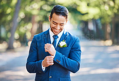 Buy stock photo Handsome groom wearing a blue suit with a white shirt and tie. Bridegroom adjusting his sleeves while standing outdoors on a sunny day