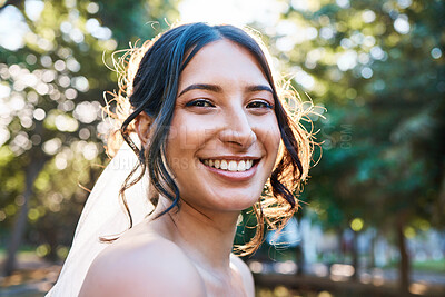 Buy stock photo Close up of a stunning mixed race bride smiling while posing against greenery on a sunny day. A happy bride wearing a veil with beautiful brown locks in a up-style and natural make-up