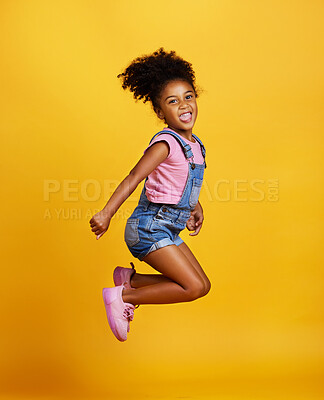 Studio portrait mixed race girl jumping into the air with her hands raised isolated against a yellow background. Cute hispanic child posing inside. Happy and carefree kid lifting her hands upwards